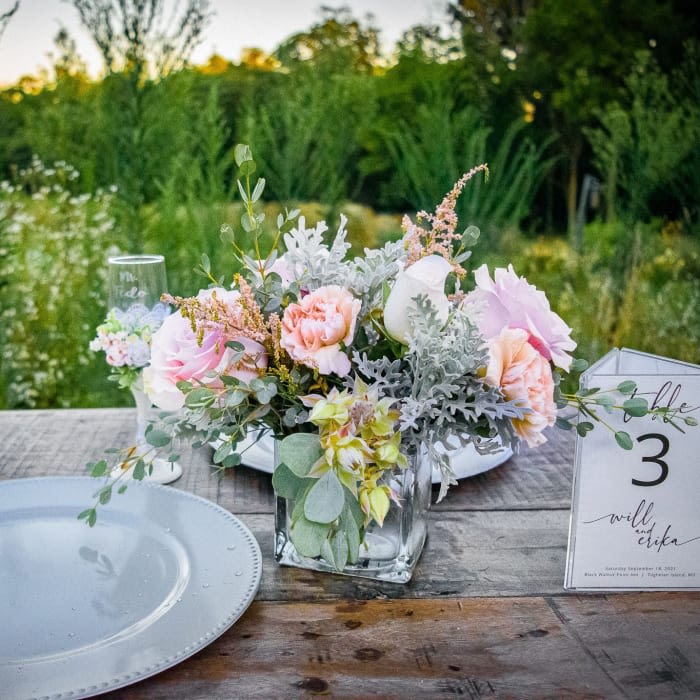 Pastel floral centerpiece in a clear glass vase on a table with a place card