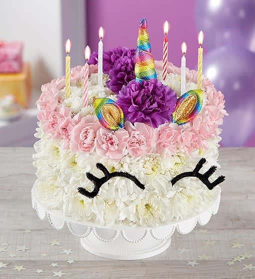 Unicorn-themed cake decorated with flowers and lit candles