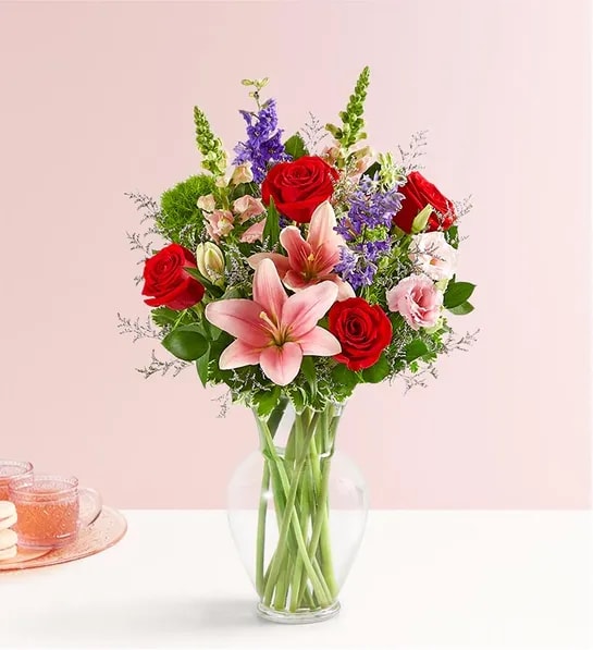 Bouquet of red roses and pink lilies in a clear glass vase