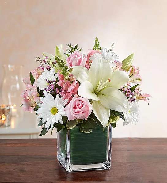 Pink and white flower arrangement in a square glass vase