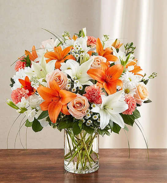 Sincerest Sorrow - Peach, Orange and White - Product ID: 95426   Express your sorrow with a memorable tribute: our bright and beautiful arrangement of lilies, roses, gladiolas, stock, daisy poms and more. Awash in soothing shades of peach, orange and white, it's hand-crafted by our florists in a classic vase for the home or service. Lush peach, orange and white arrangement of roses, lilies, gladiolas, stock, daisy poms, carnations and monte casino, accented with variegated pittosporum, salal, myrtle and bear grass Hand-designed by our select florists in a classic glass cylinder vase; vase measures 8"H Can be sent to the home of friends, family members or business associates, or to the funeral service Large arrangement measures approximately 24"H x 22"L Medium arrangement measures approximately 22"H x 20"L Small arrangement measures approximately 20"H x 18"L Our florists hand-design each arrangement, so colors, varieties, and container may vary due to local availability Lilies may arrive in bud form and will open to full beauty over the next 2-3 days