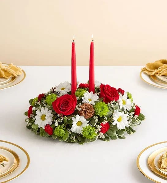 Red candles in a low floral centerpiece with white daisies and red roses