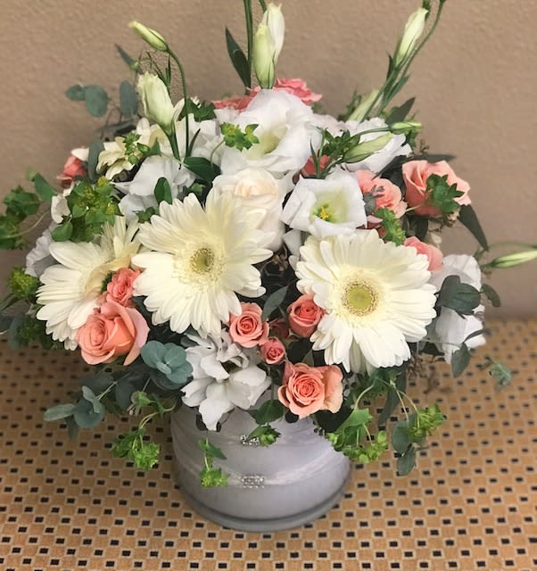 Bouquet of white gerbera daisies and peach roses in a gray vase