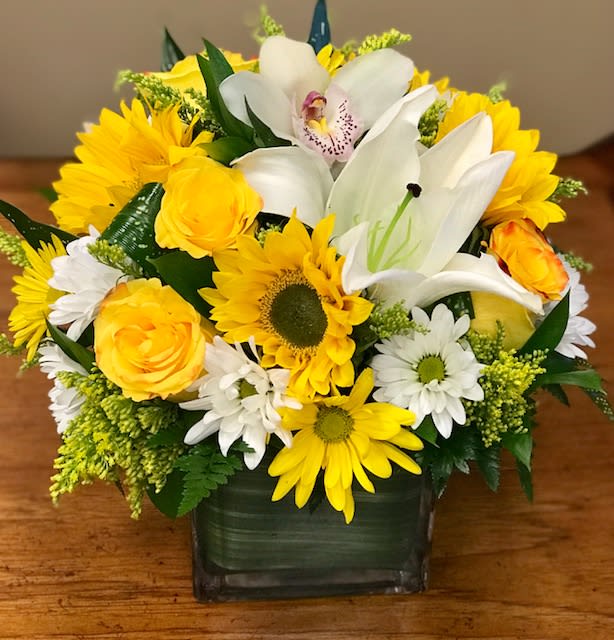 Yellow and white mixed flower arrangement in a square glass vase