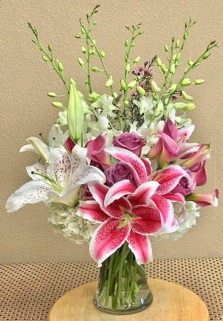 Pink and white lilies with roses in a glass vase