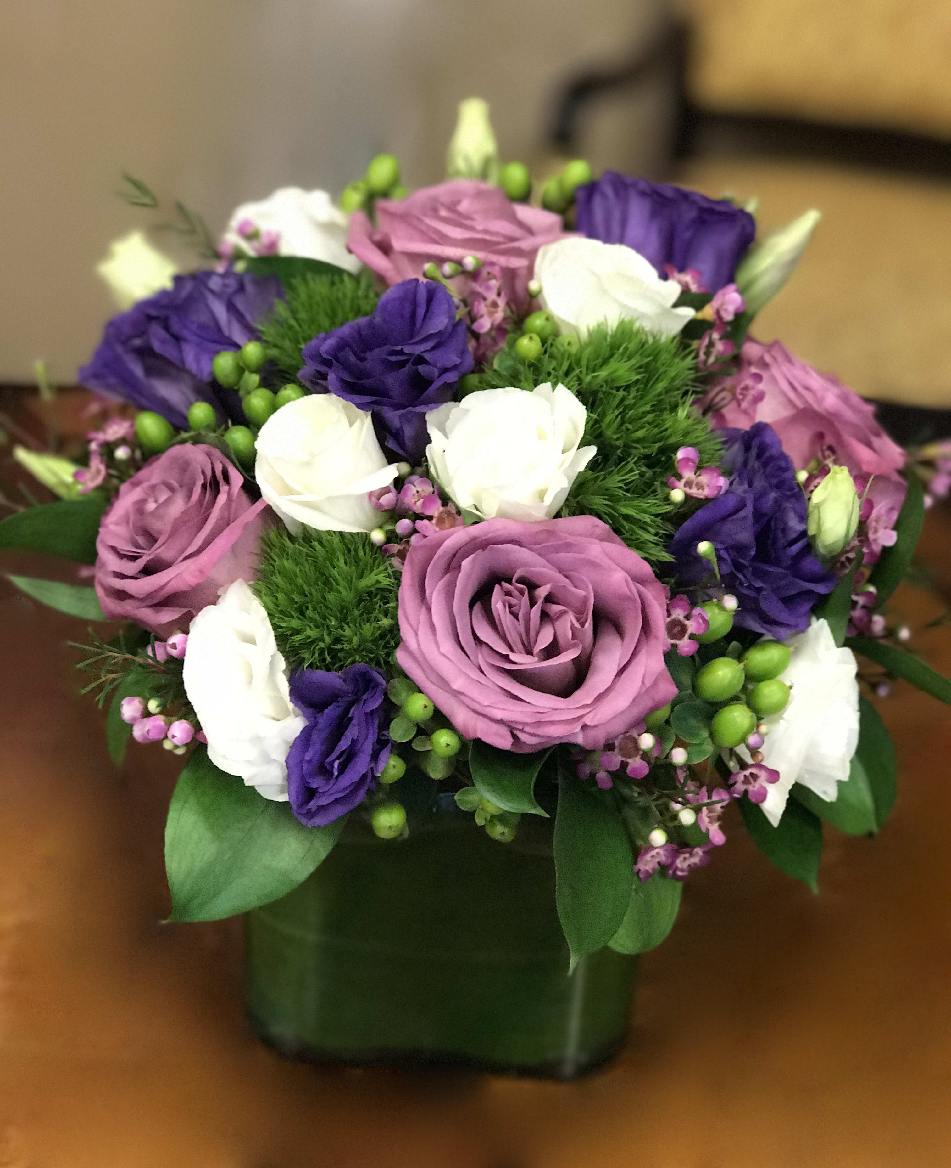Bouquet of pink, purple, and white roses in a square vase