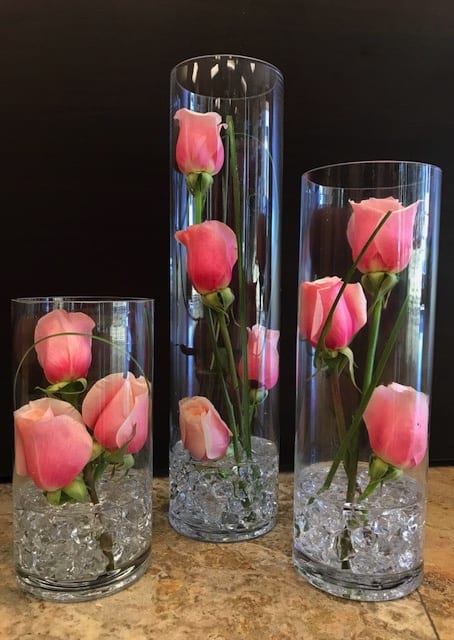 Pink roses arranged in three clear glass cylinder vases