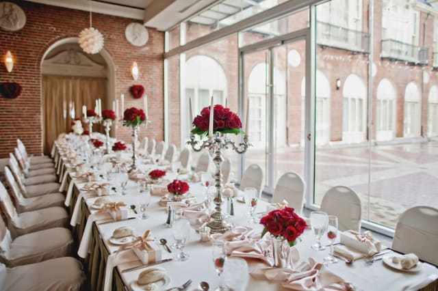 Long banquet table with red rose centerpieces and white candles