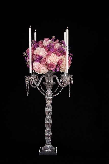 Pink and purple floral arrangement on a tall crystal candelabra.