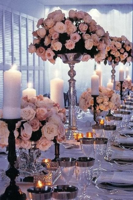 Pink rose centerpieces with white candles on a formal table setting