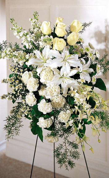 White and pale yellow floral standing spray on a black easel
