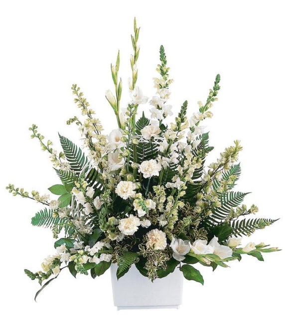 White floral arrangement in a square white vase with tall greenery