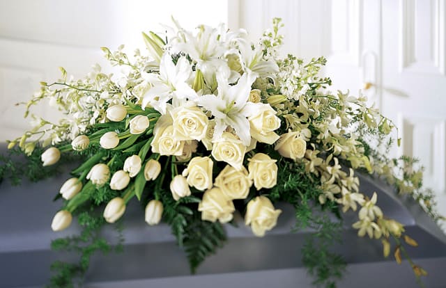 White lilies and cream roses arranged on a casket