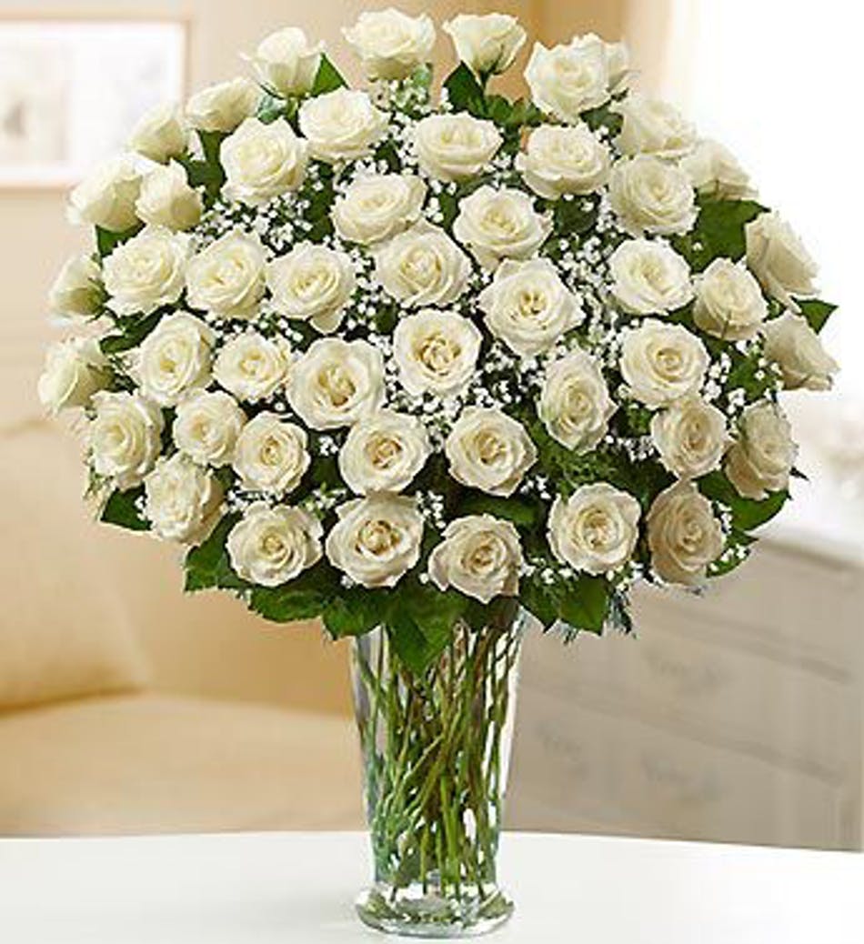 White roses arranged in a clear glass vase with baby's breath