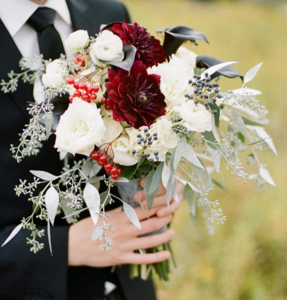 Bride holding a bouquet of white and burgundy flowers
