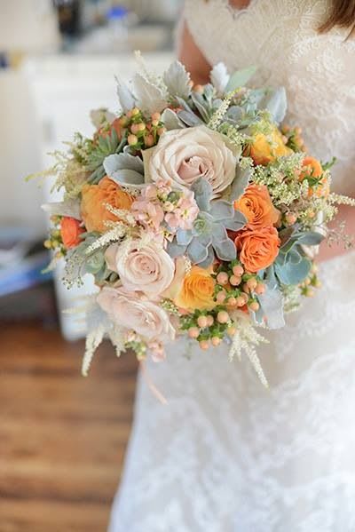 Bridal bouquet with pale roses, orange blooms, and blue-gray succulents