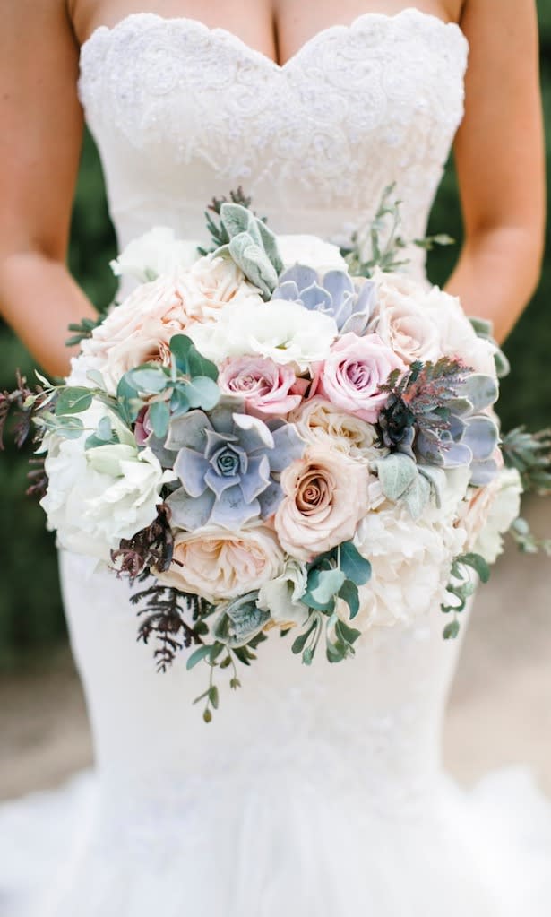 Bride holding a pastel bouquet of roses and succulents