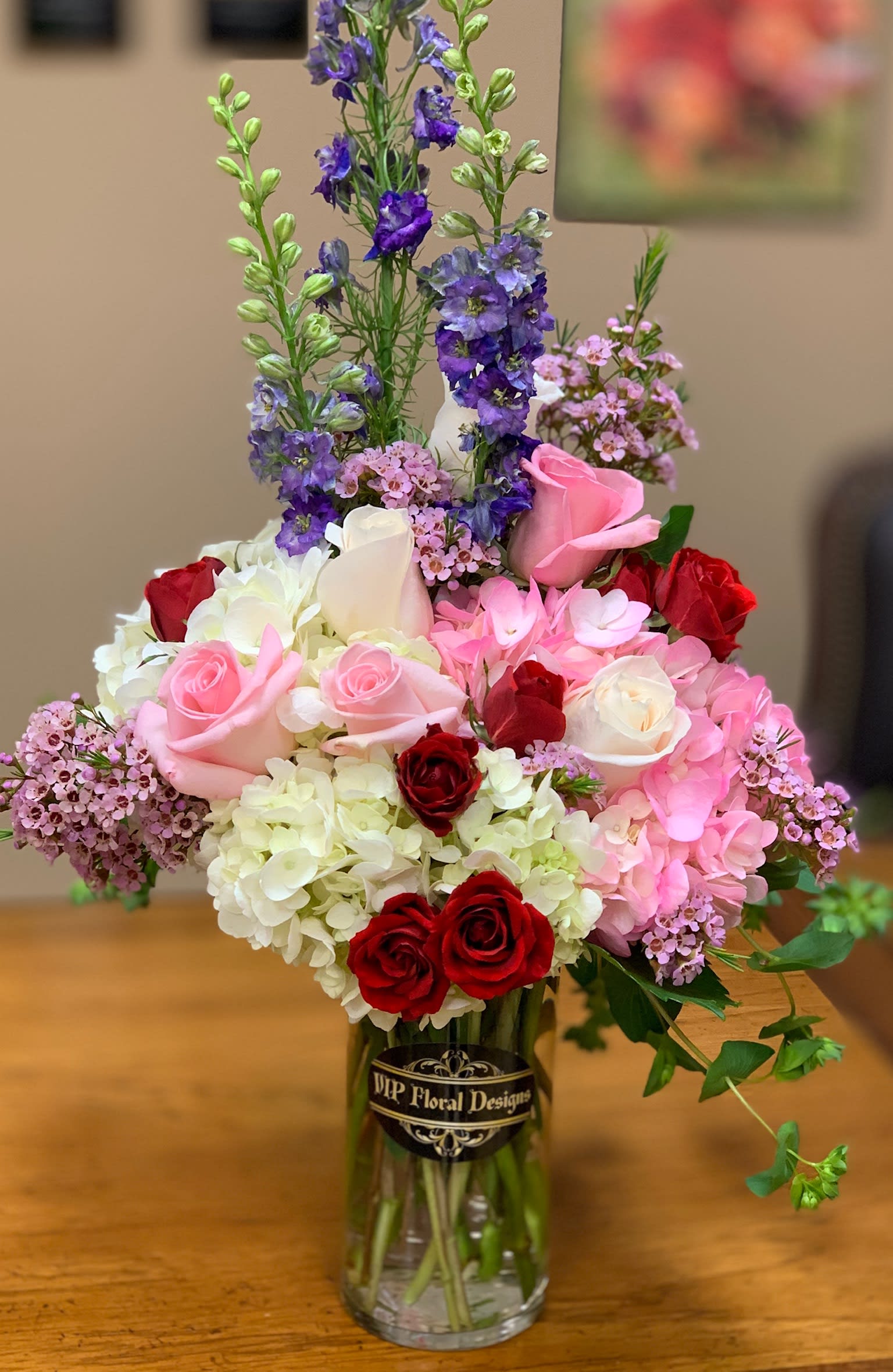 Mixed bouquet of roses, hydrangeas, and purple flowers in a glass vase
