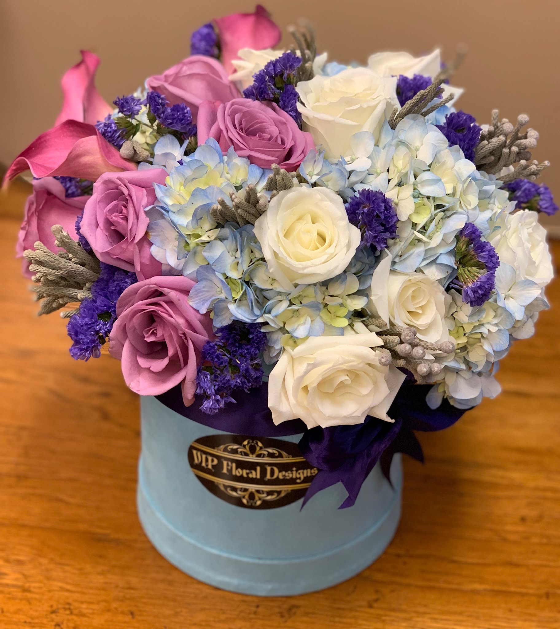 Bouquet of pink and white roses with blue hydrangeas in a round box