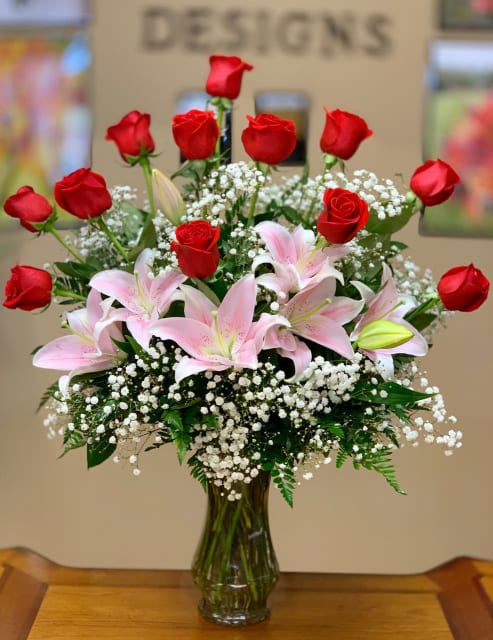 Red roses and pink lilies arranged in a clear glass vase