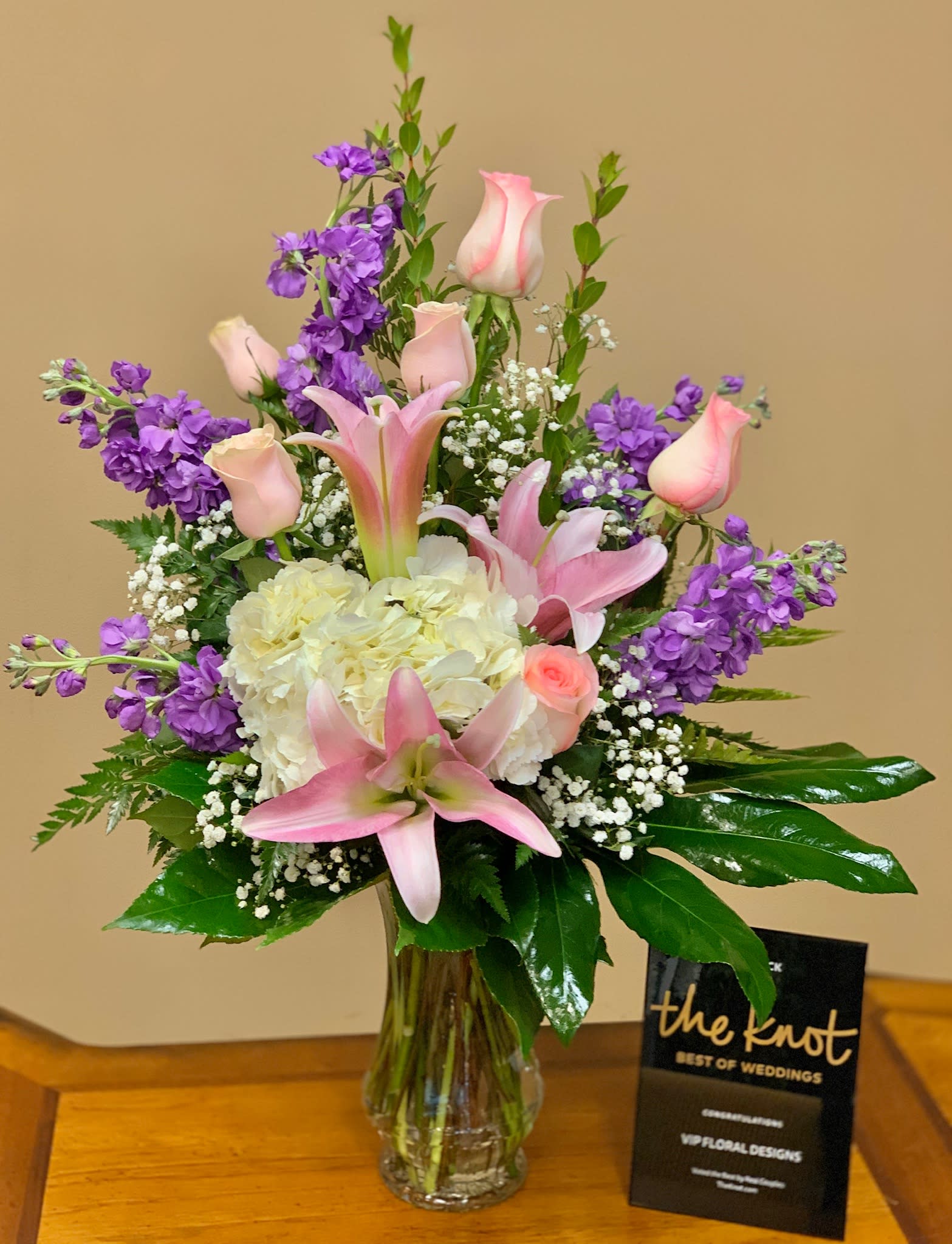 Pink lilies and roses with purple stock in a glass vase