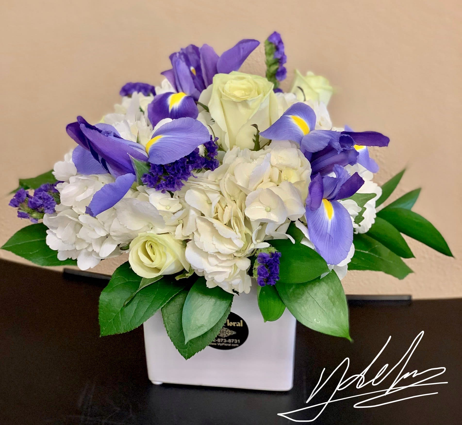 Bouquet of white roses, hydrangeas, and purple irises in a white vase