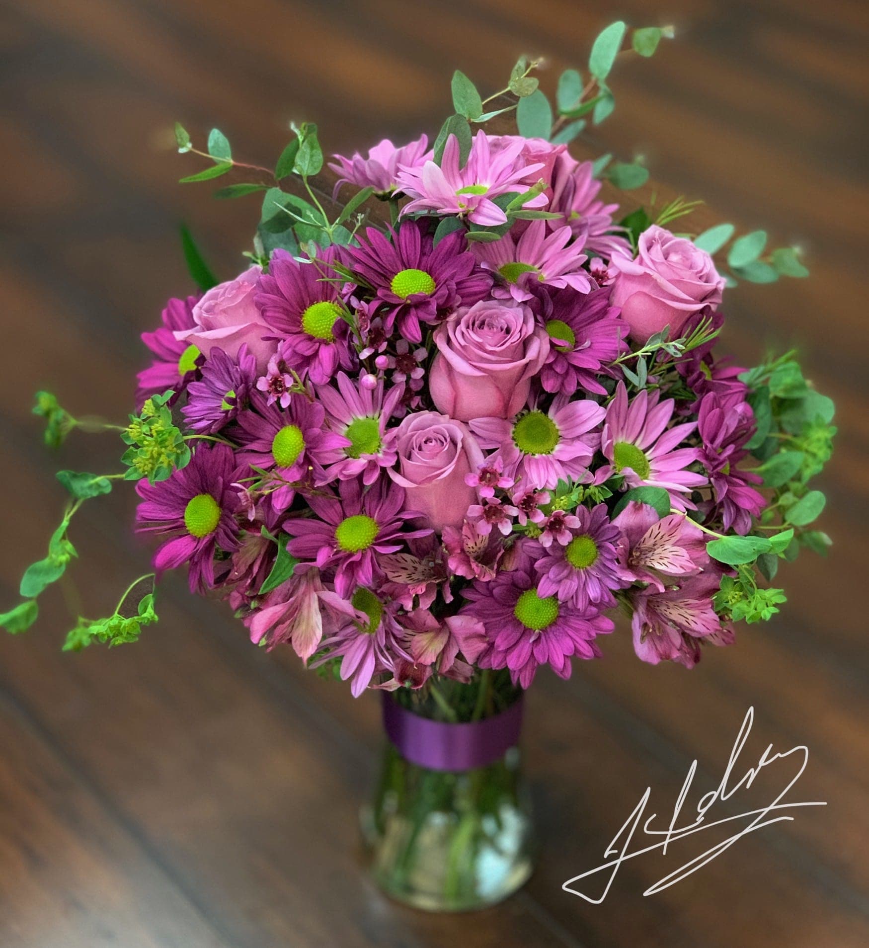 Pink and purple bouquet of roses and daisies in a glass vase