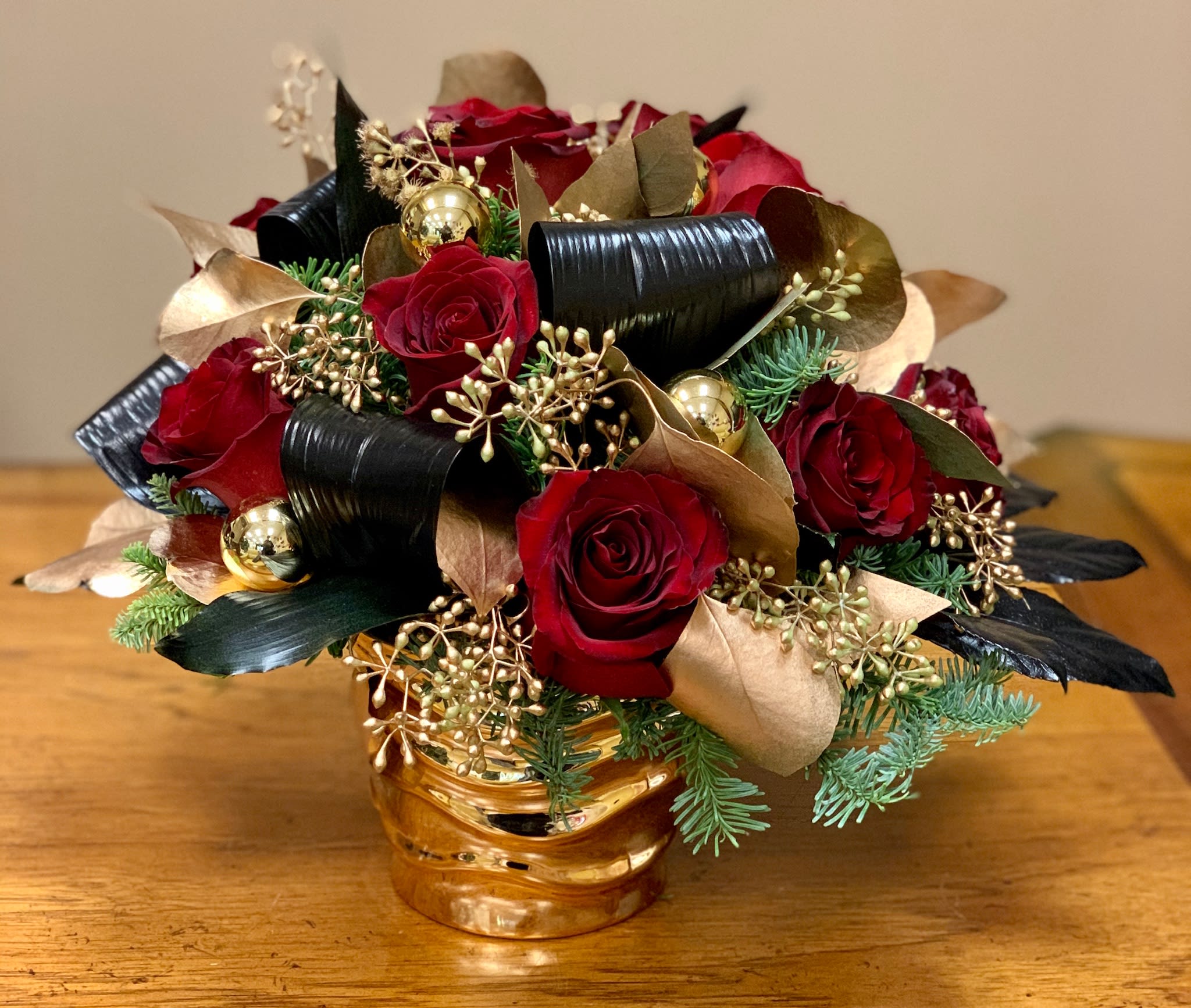 Red roses arranged with gold accents in a gold vase