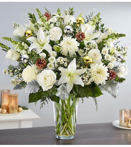 White lilies and roses in a clear glass vase with pinecones and ornaments