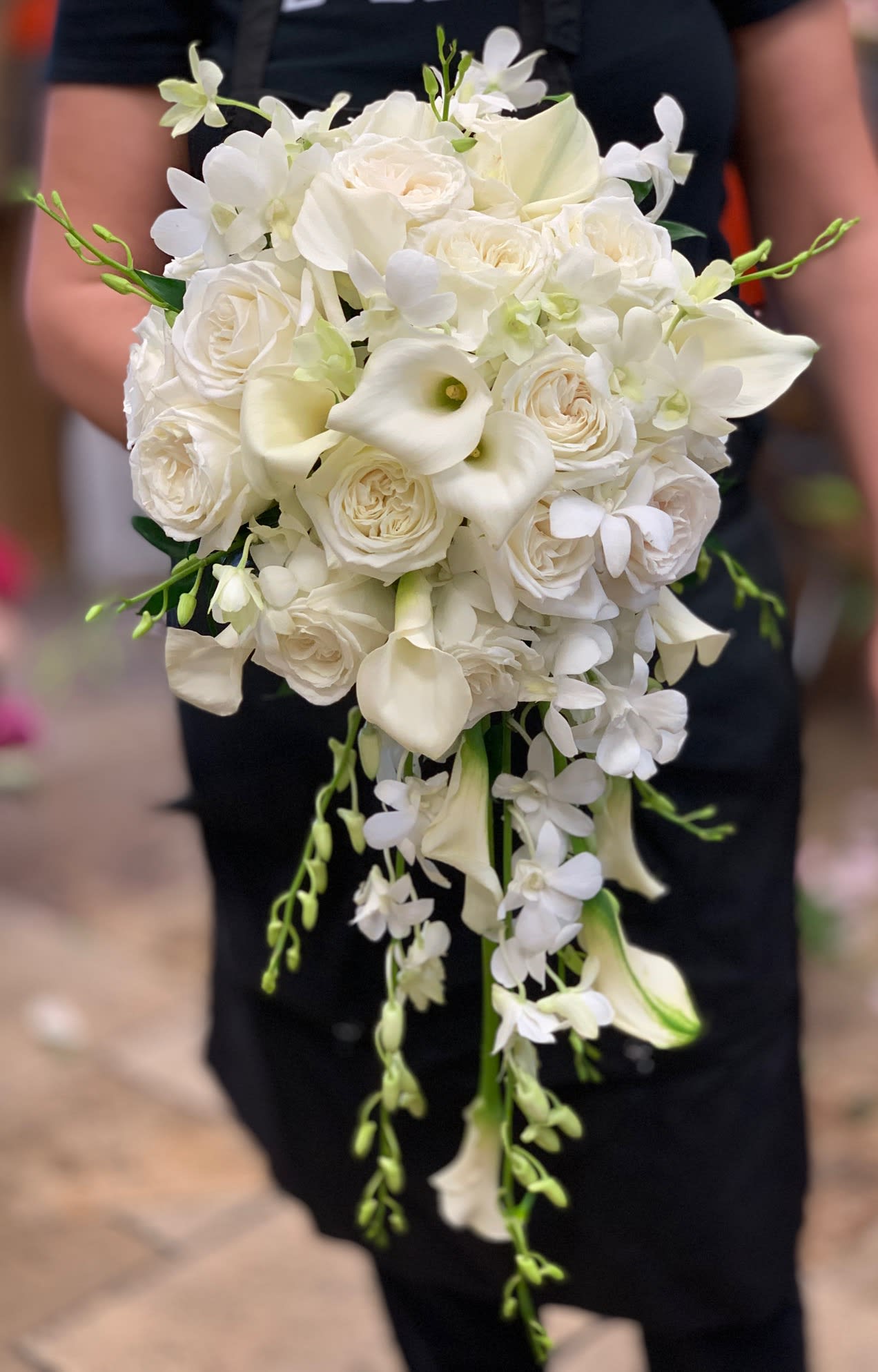 White bridal bouquet with roses, calla lilies, and trailing orchids