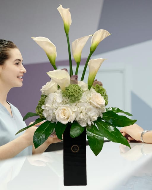 White calla lilies and roses arranged in a black vase