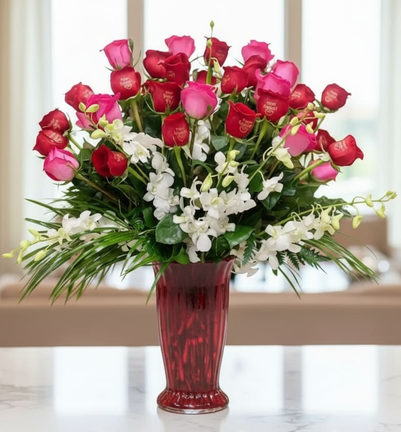 Bouquet of red and pink roses with white orchids in a red vase