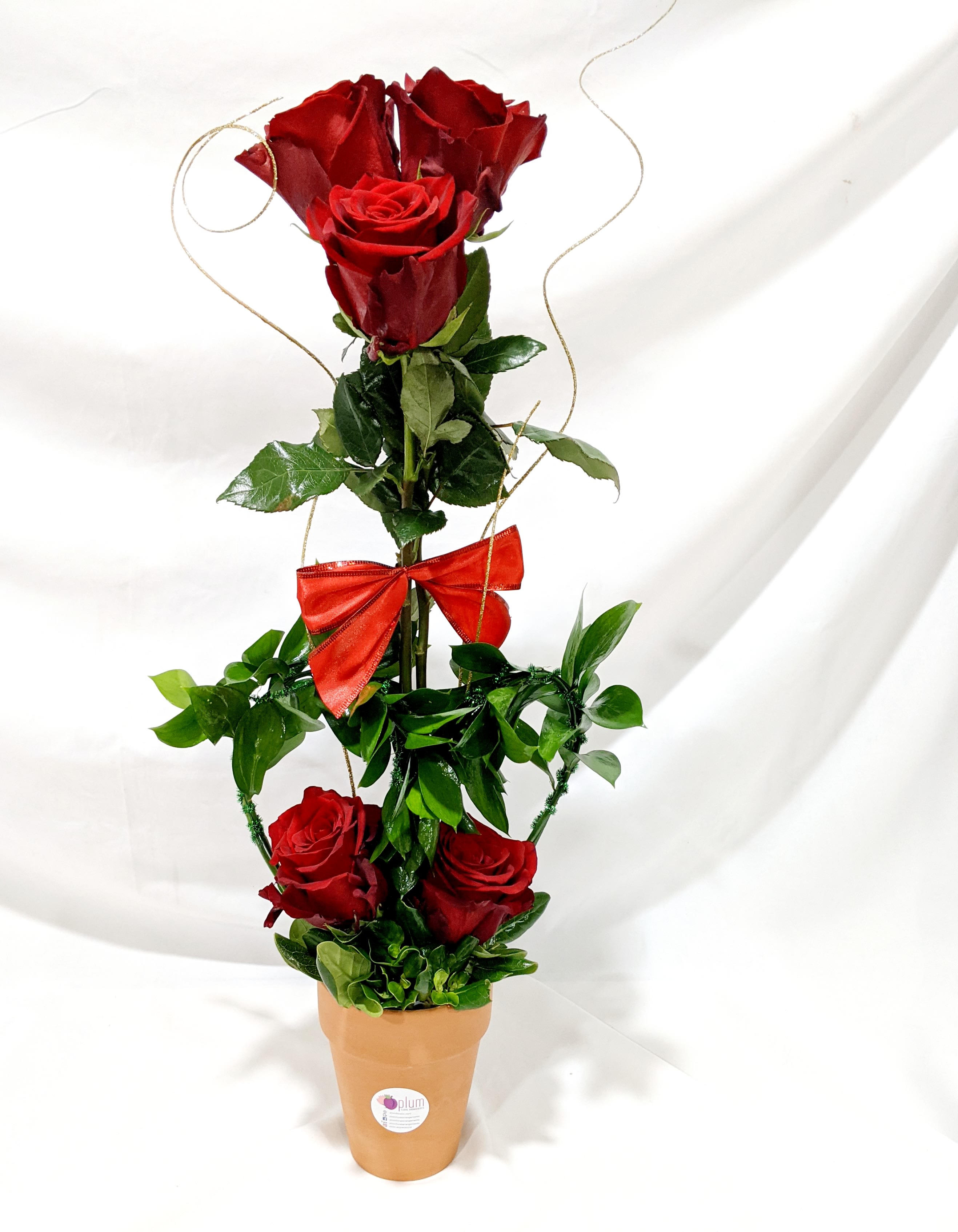 Tall arrangement of red roses in a terracotta pot with a red bow