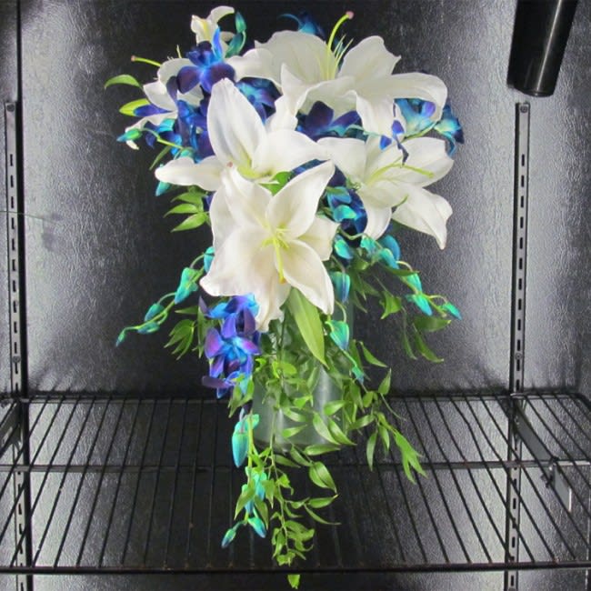 White lilies with blue-purple orchids in a glass vase