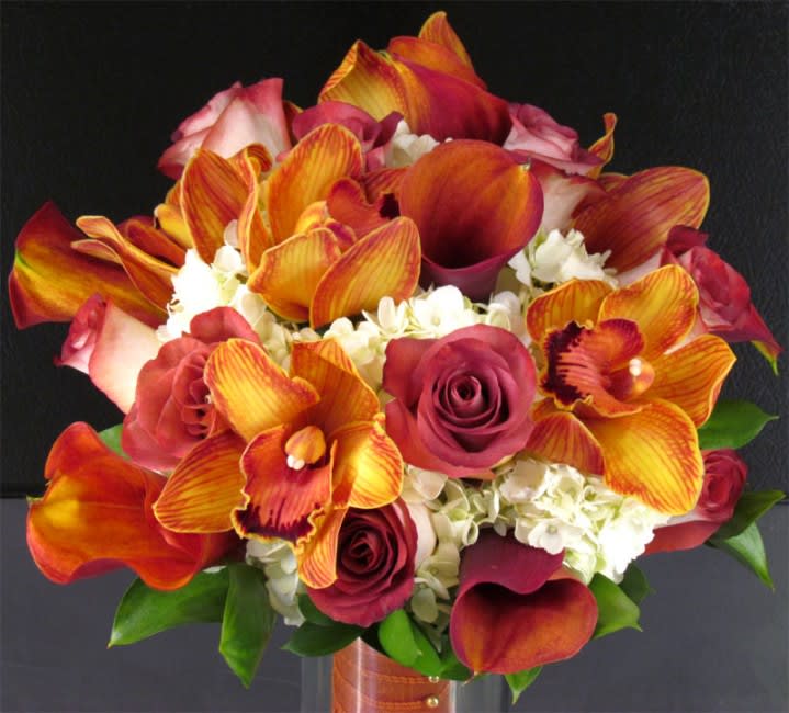 Bouquet of orange orchids, burgundy roses, and white hydrangeas in a vase