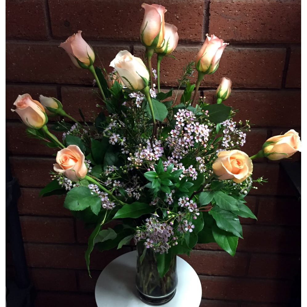 Peach roses and small pink flowers in a glass vase