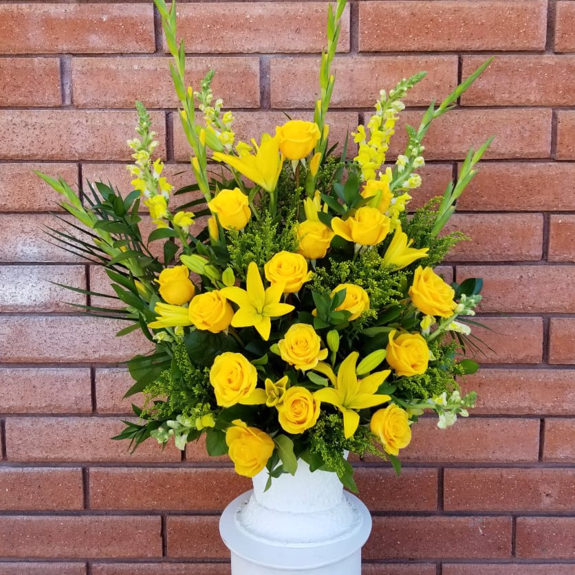 Yellow roses and lilies arranged in a white vase