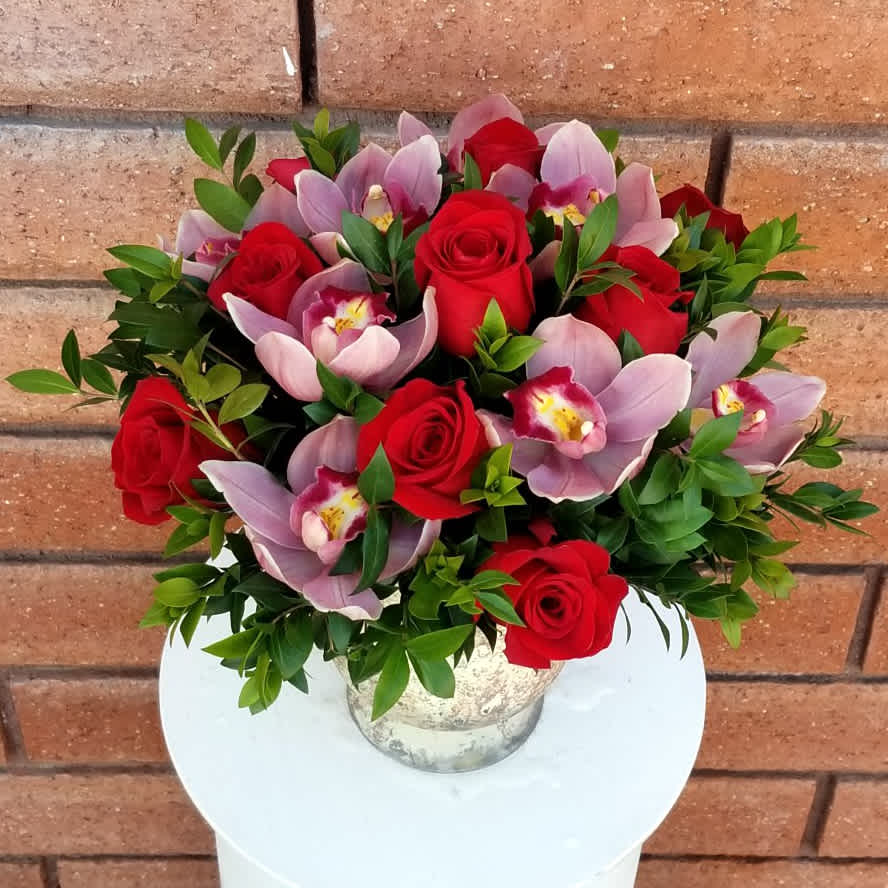 Bouquet of red roses and pink orchids in a silver vase