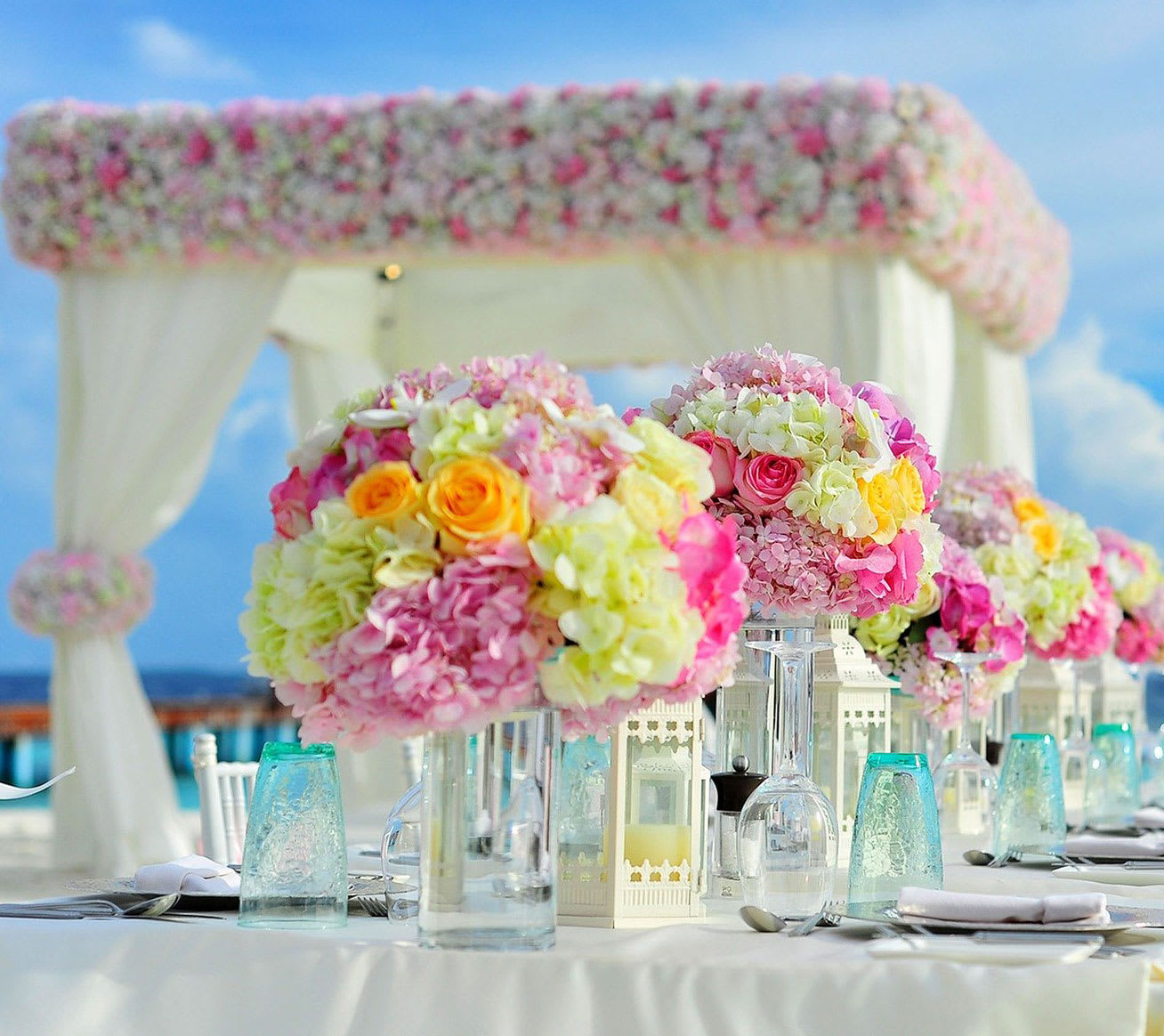 Pink and white floral centerpieces on a decorated outdoor table