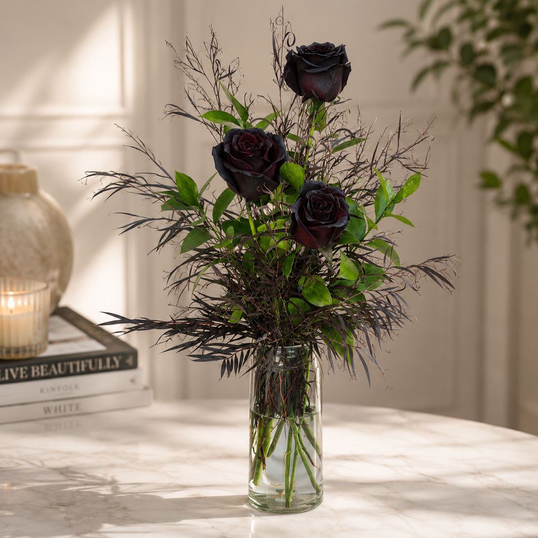 Enchanted Black Rose Vase - Enchanted Black Rose Vase  Dramatic, elegant, and unforgettable — our Enchanted Black Rose Vase is designed to leave a lasting impression. Featuring premium long-stem black roses arranged in a sleek glass vase with fresh greenery and agonis, this unique bouquet is perfect for anniversaries, romantic gestures, or anyone who loves flowers with a bold twist. Available for same-day black rose delivery in San Diego, it’s a gift that speaks of mystery and timeless beauty.  Please note: Black roses are not naturally black; these roses are color-dyed to achieve their dramatic, striking hue.  Size Options:  • Standard – 3 Black Roses with premium greenery and agonis in a glass vase.  • Deluxe – 6 Black Roses with added greenery and agonis for a fuller look.  • Premium – 12 Black Roses with lush greenery and agonis in a glass vase for a breathtaking display.  Approximate size (Standard): 16" H x 7" W