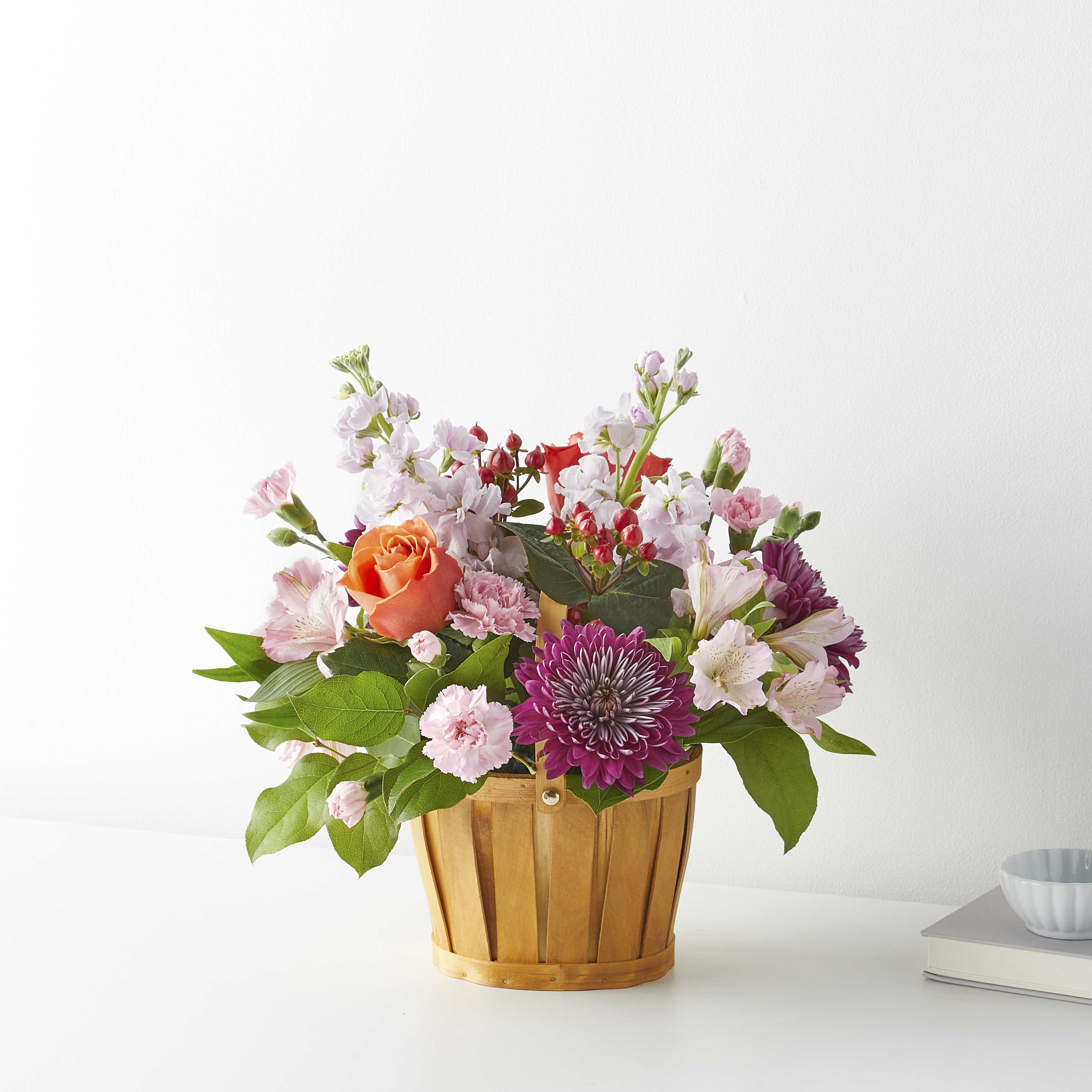 Mixed pink and purple flowers in a wooden basket