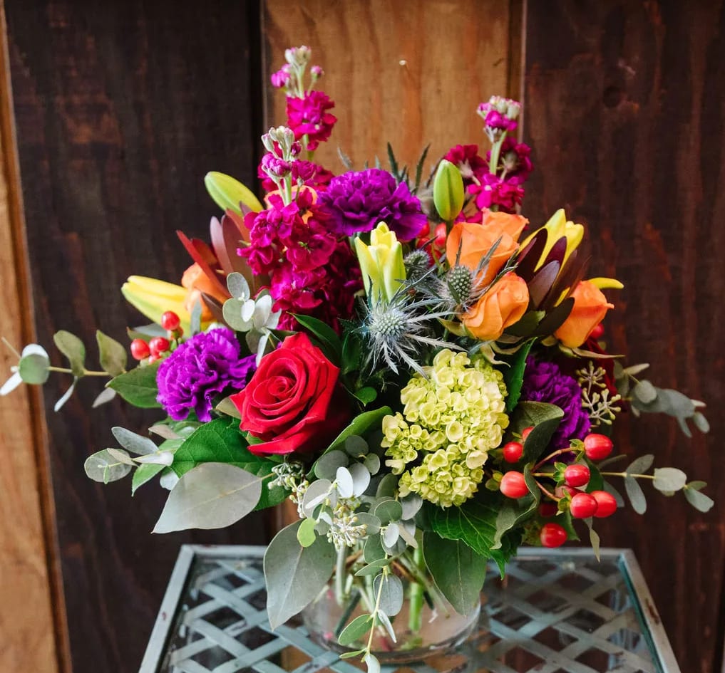 Autumn Jewels - As mesmerizing as an autumn sunset, this majestic mix of radiant blooms is a gift they will treasure.  This arrangement includes bright fall colors in purples, yellows, oranges reds and fuchsia, designed in a 5" low cylinder vase.
