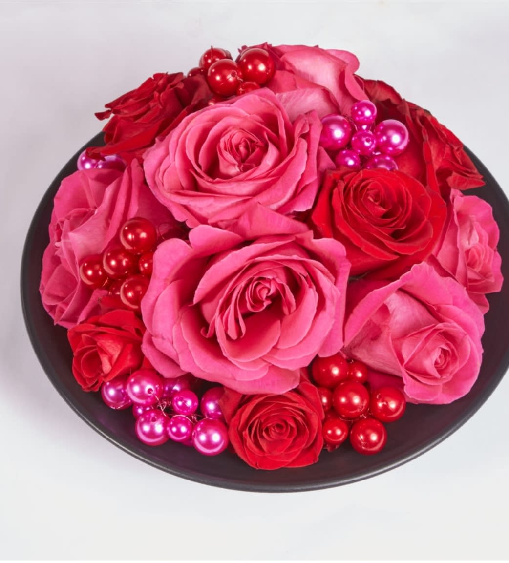Round box of pink and red roses with shiny berry accents