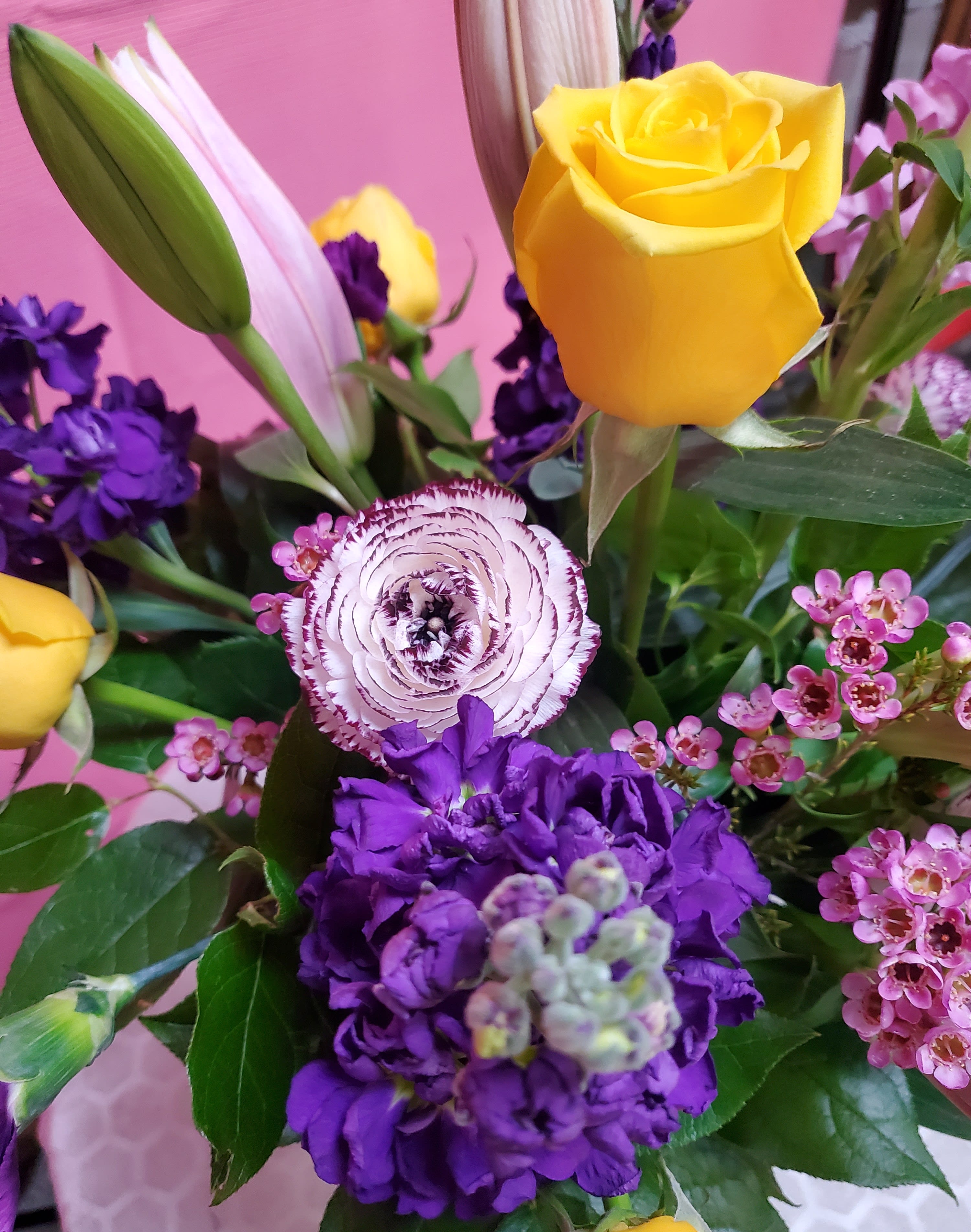Bouquet with yellow roses, purple blooms, and a pink-striped ranunculus