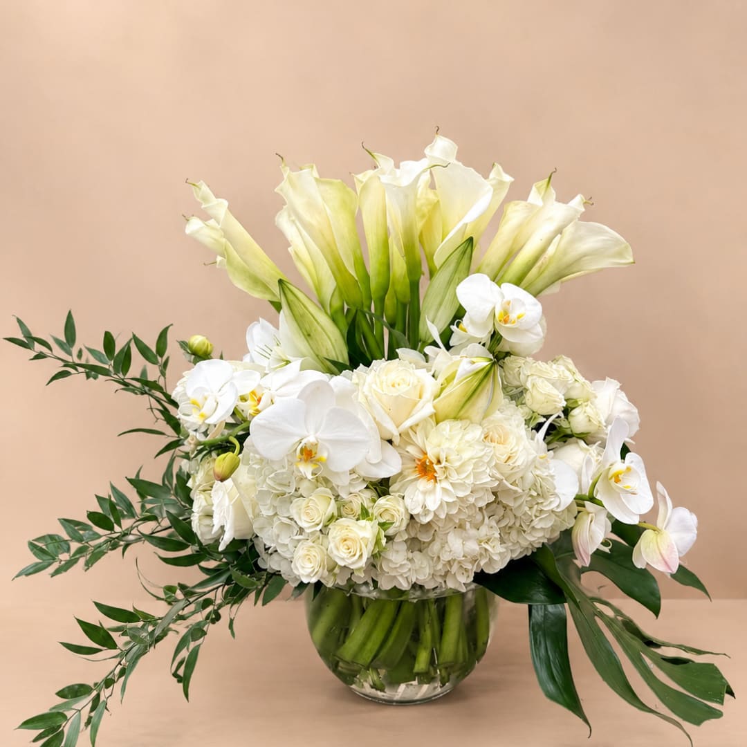 White calla lilies, orchids, and roses arranged in a glass vase