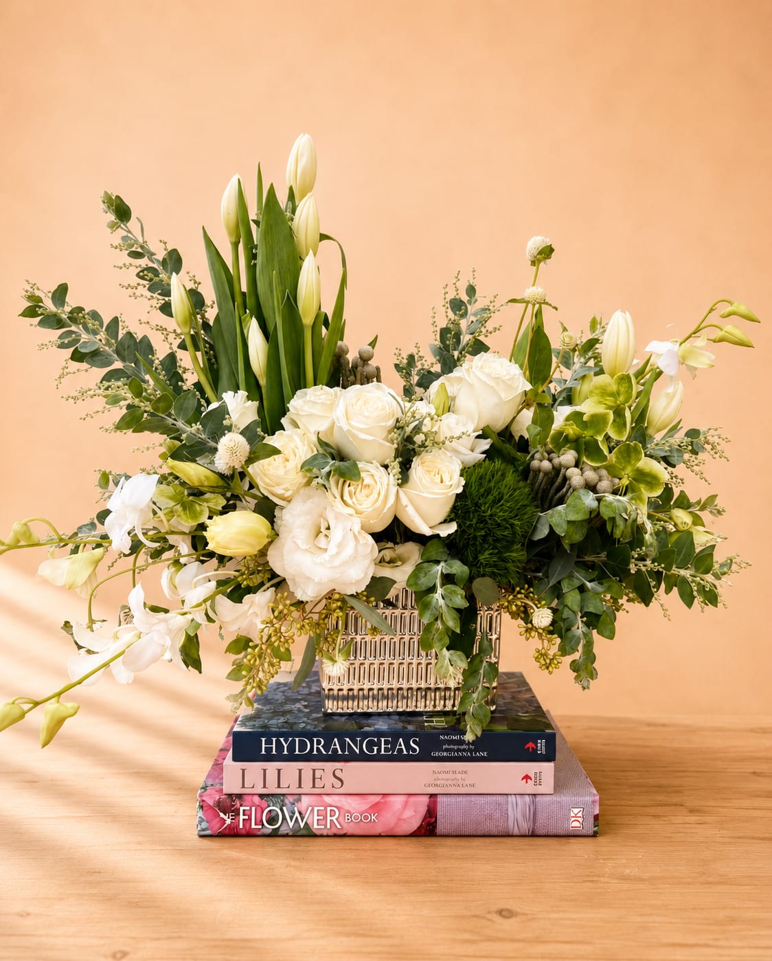 White roses and lilies arranged in a square vase with greenery