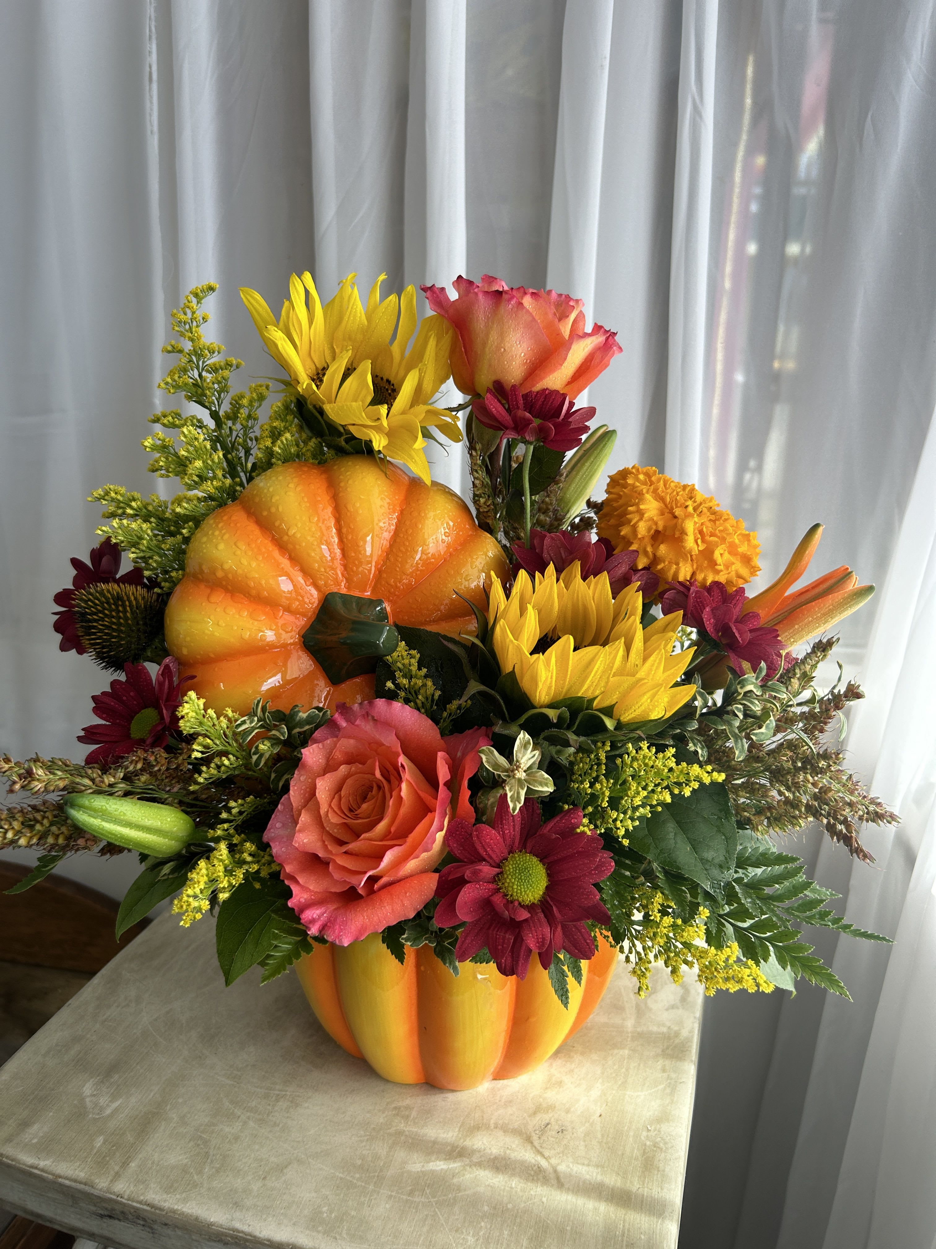 Pumpkin-shaped floral arrangement with sunflowers, roses, and mums