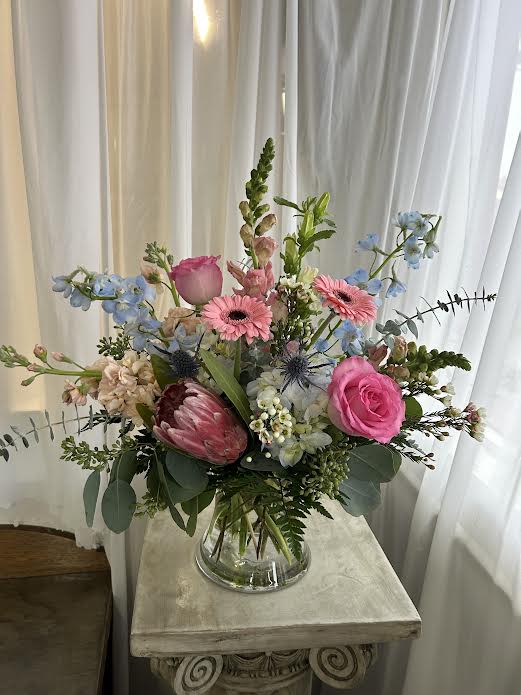 Mixed bouquet in a clear glass vase with pink and blue flowers