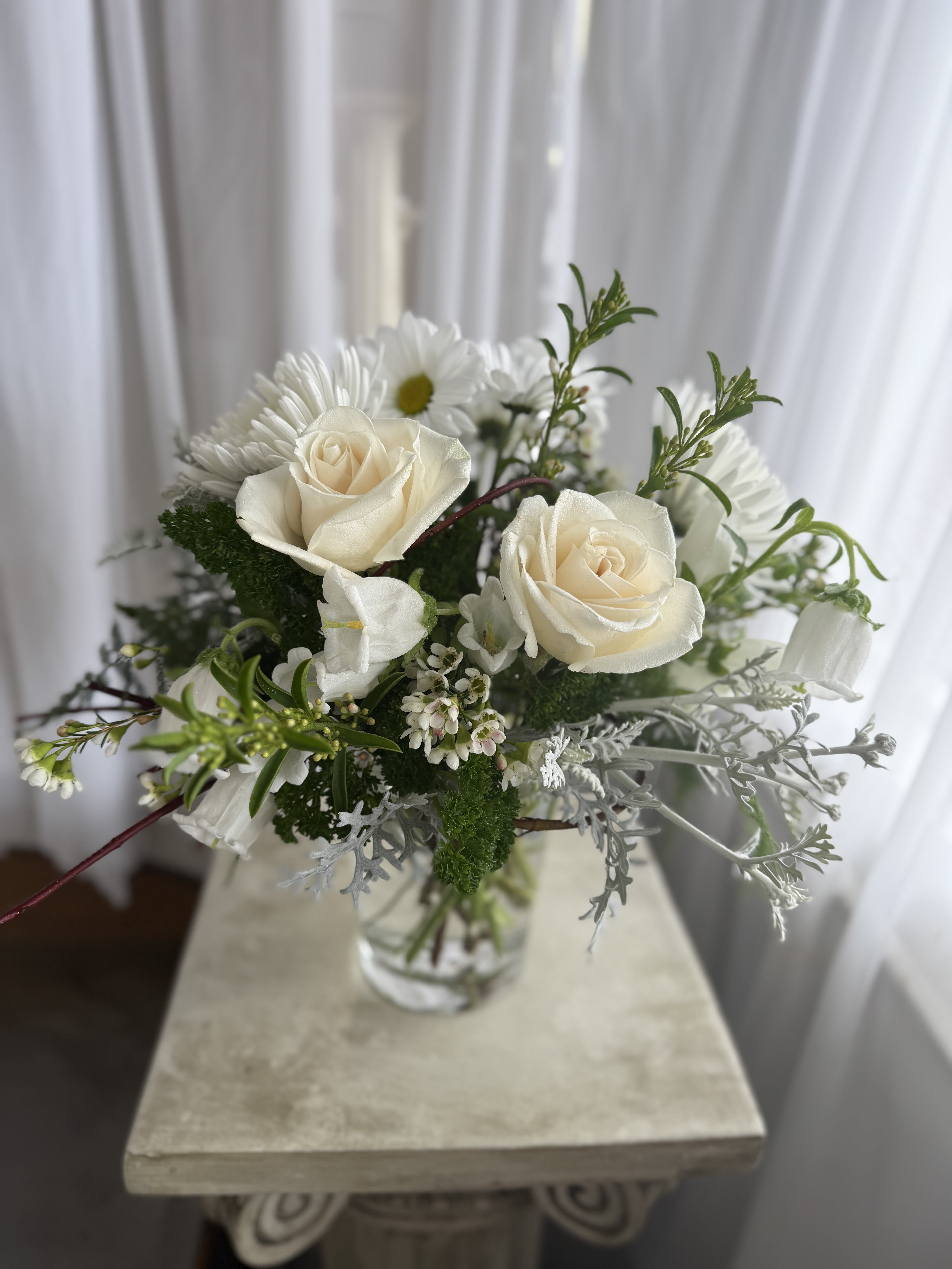 White roses and daisies in a clear glass vase