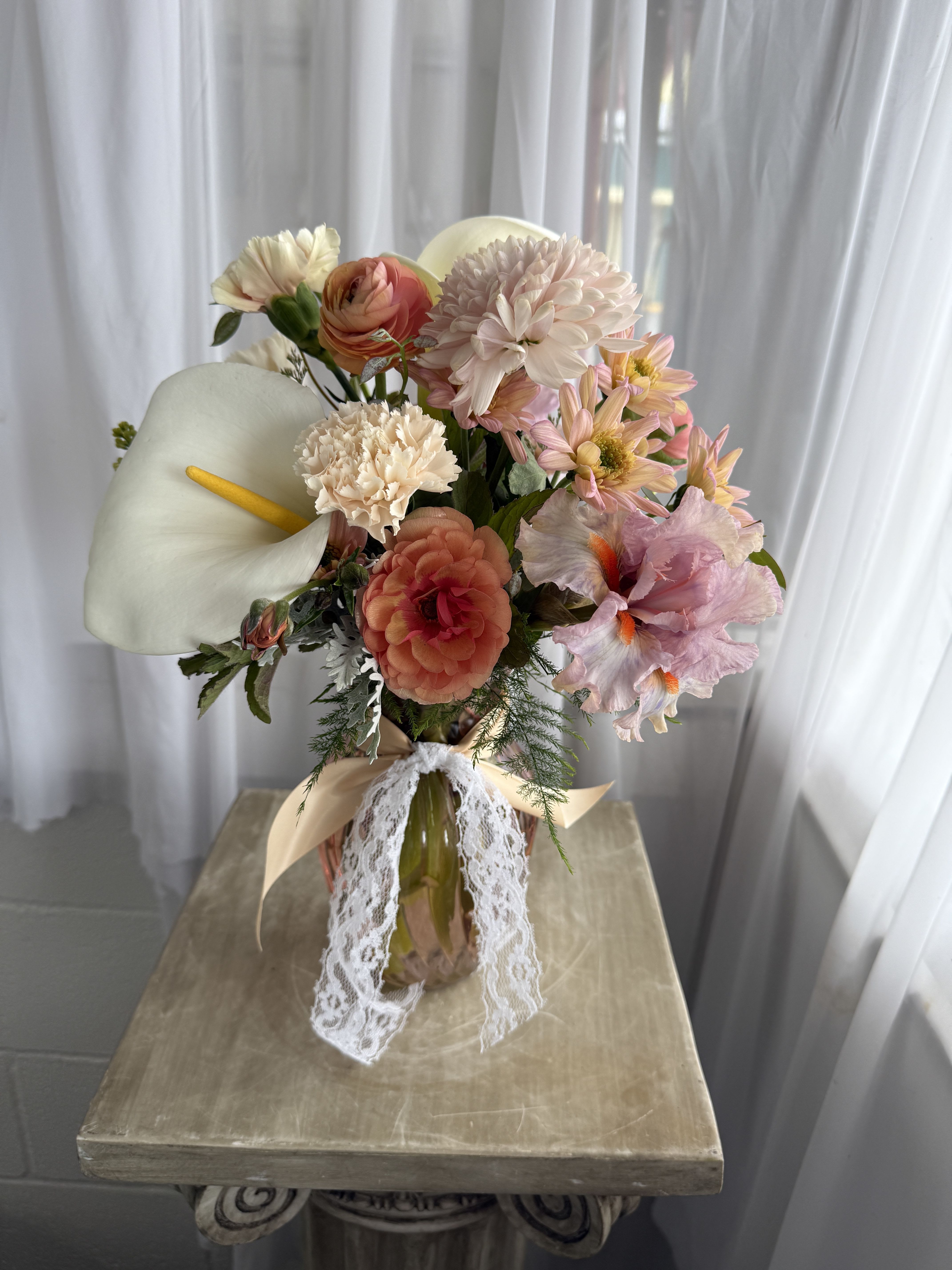 Mother of Mine - A pastel vase is filled with calla lilies, iris, lilac, ranunculus, and more.  As always, vase and flowers may be substituted depending on what is in stock.  Call shop to find out exactly what we will be using.